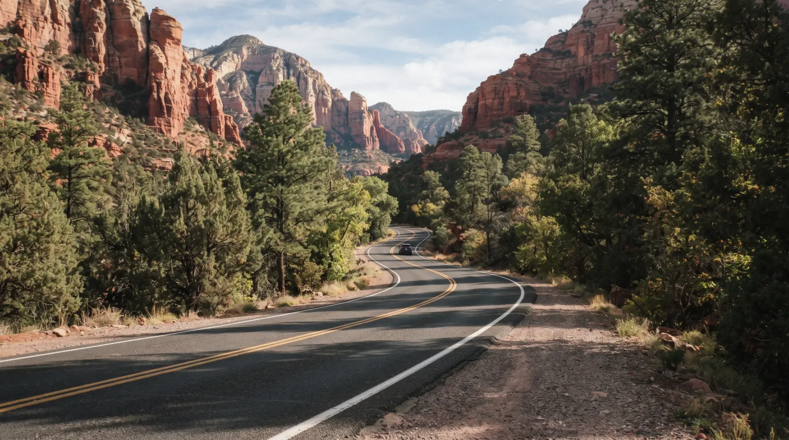 A two-lane highway curving through red rock country outside Sedona Arizona, the road one of the day trips from Sedona leading toward the Grand Canyon and Verde Valley