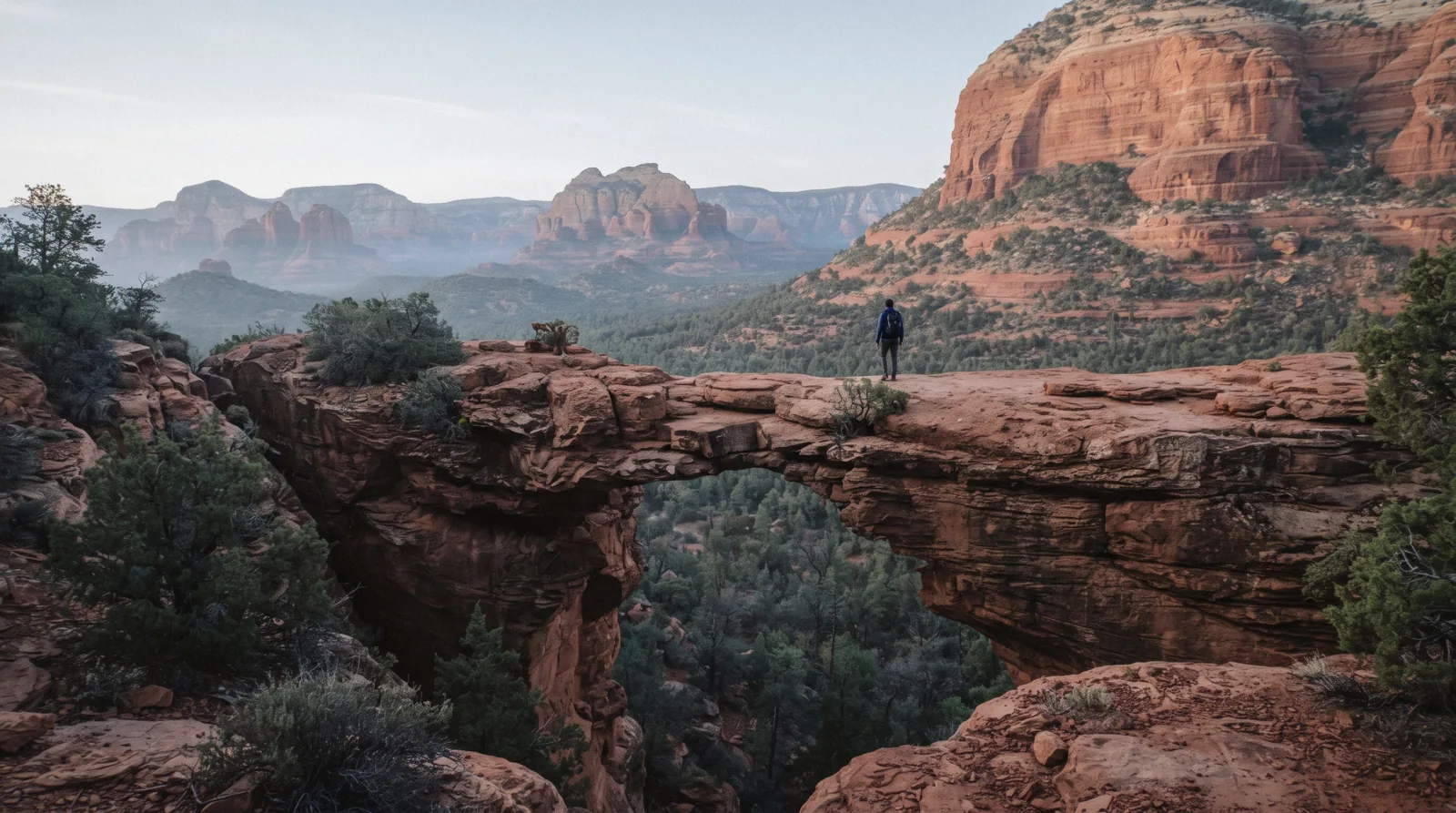 Hikers crossing the natural sandstone arch of Devil's Bridge above the Dry Creek basin, Devil's Bridge Sedona
