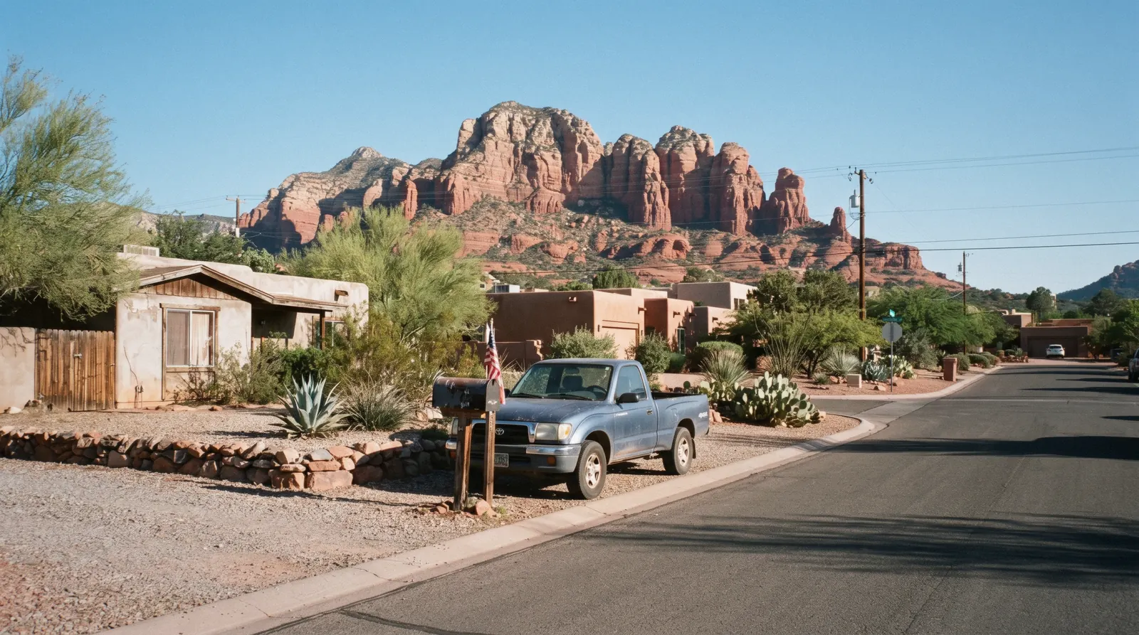 Red rock formations rising behind a road junction at sunset, the Sedona neighborhoods that ring the town