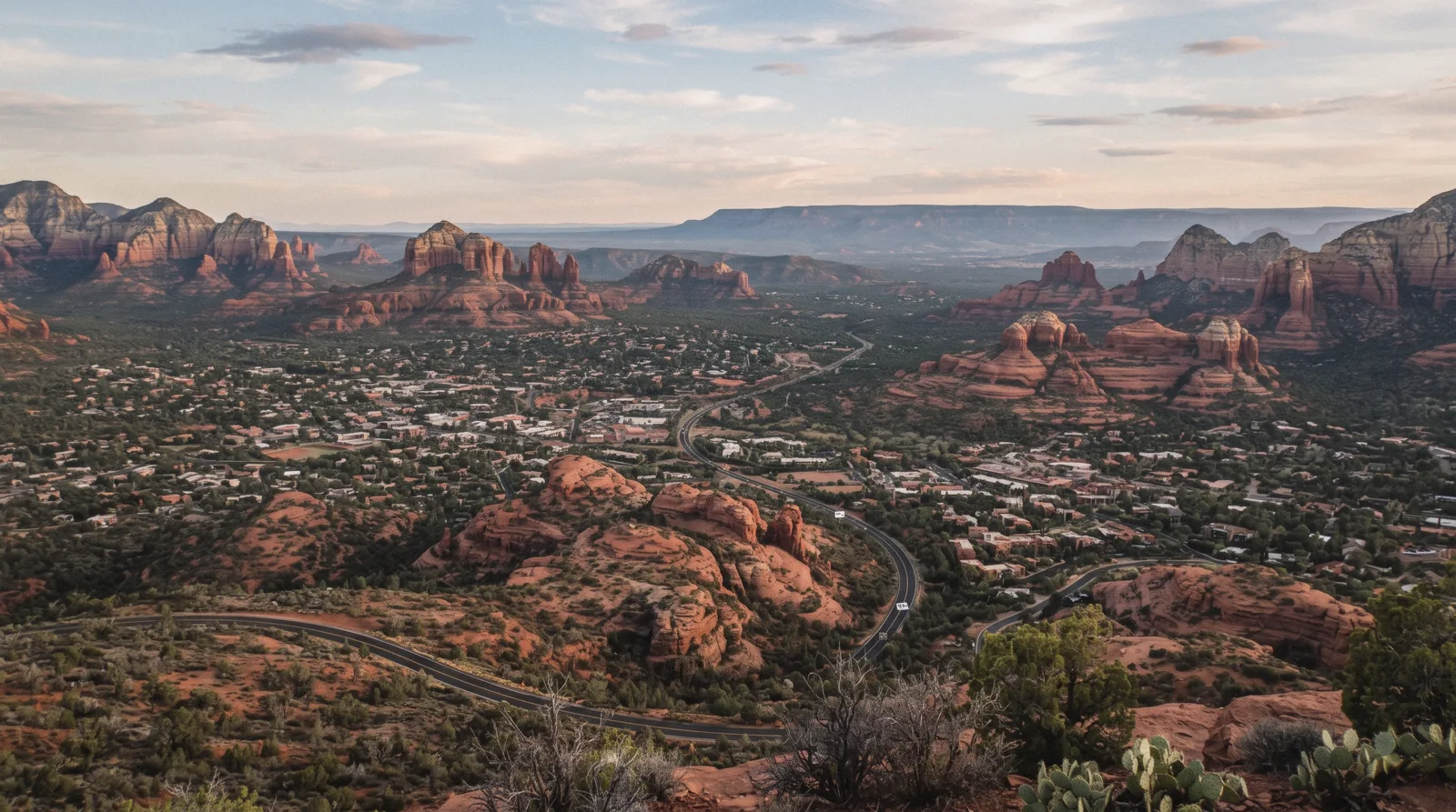 An aerial-feeling wide view over the Sedona Arizona basin from Airport Mesa Road at sunset, red buttes threading the town on this Sedona map orientation page