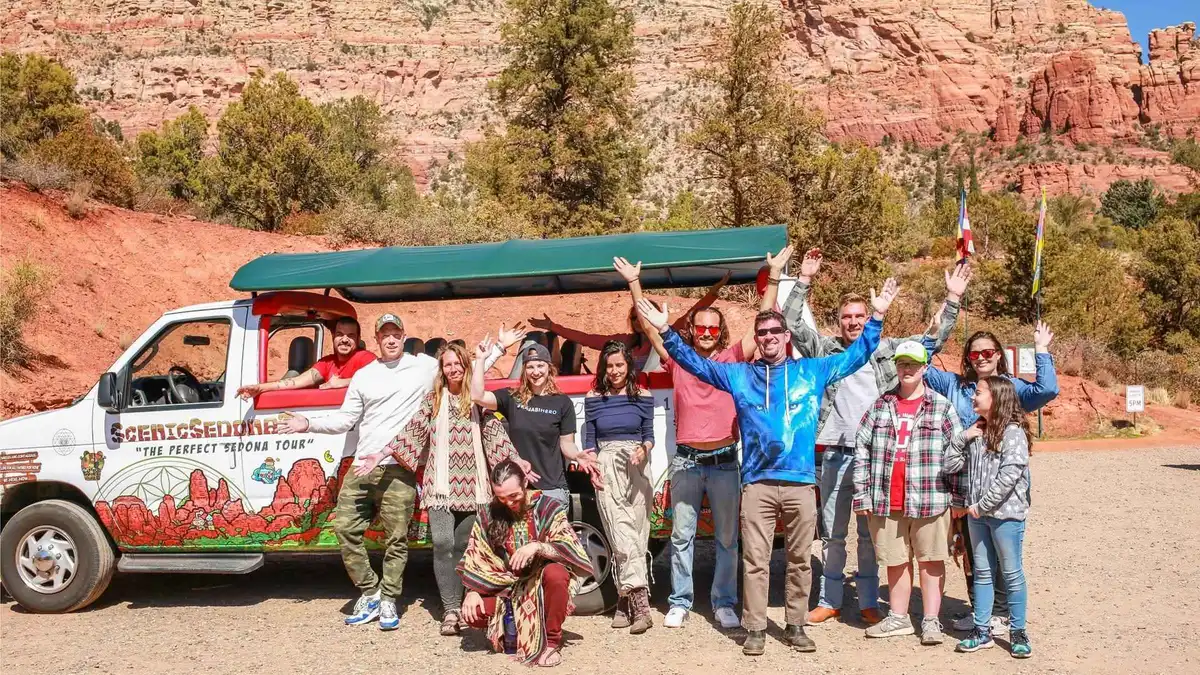 Open-air sightseeing bus stopped at a red rock viewpoint in Sedona