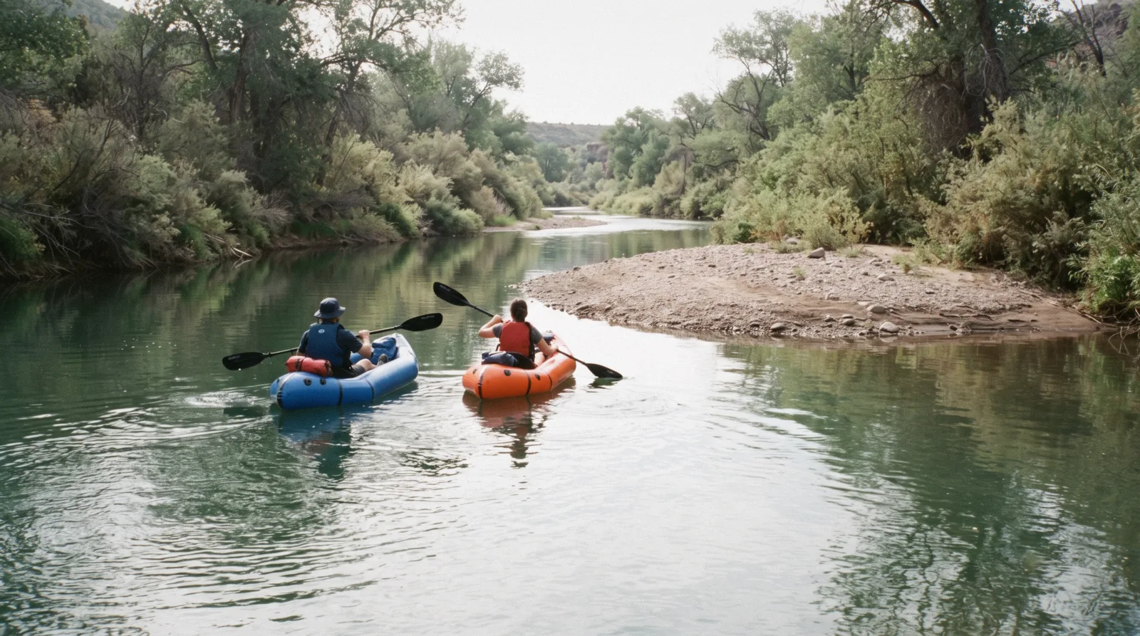 A paddler in an inflatable kayak on a green stretch of the Verde River near Clarkdale, with cottonwoods on the banks, on a Verde River kayaking trip